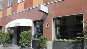 A Holiday Homes Milano building with a storefront, large windows, and potted plants. - Holiday Homes Aparthotel Milano (Milan)