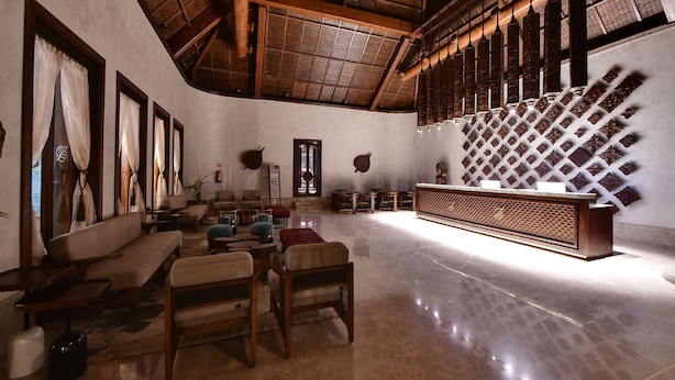 A spacious lobby with a high ceiling, wooden ceiling beams, a reception desk, and seating area with chairs and sofas. - Maira Resort and Convention centre (Arang)