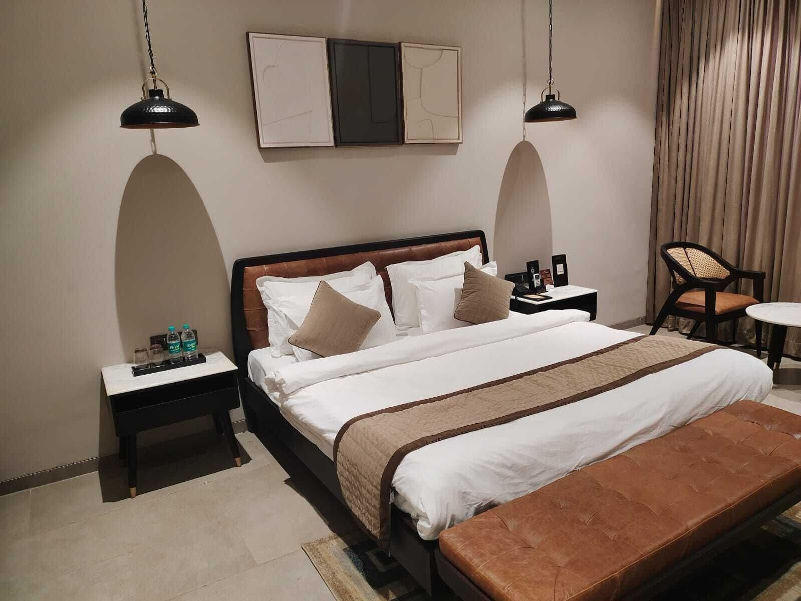 Une chambre d’hôtel avec un grand lit, deux tables de chevet, une petite table d’appoint, une chaise et une petite table.