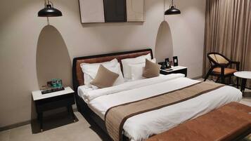 Une chambre d’hôtel avec un grand lit, deux tables de chevet, une petite table d’appoint, une chaise et une petite table.