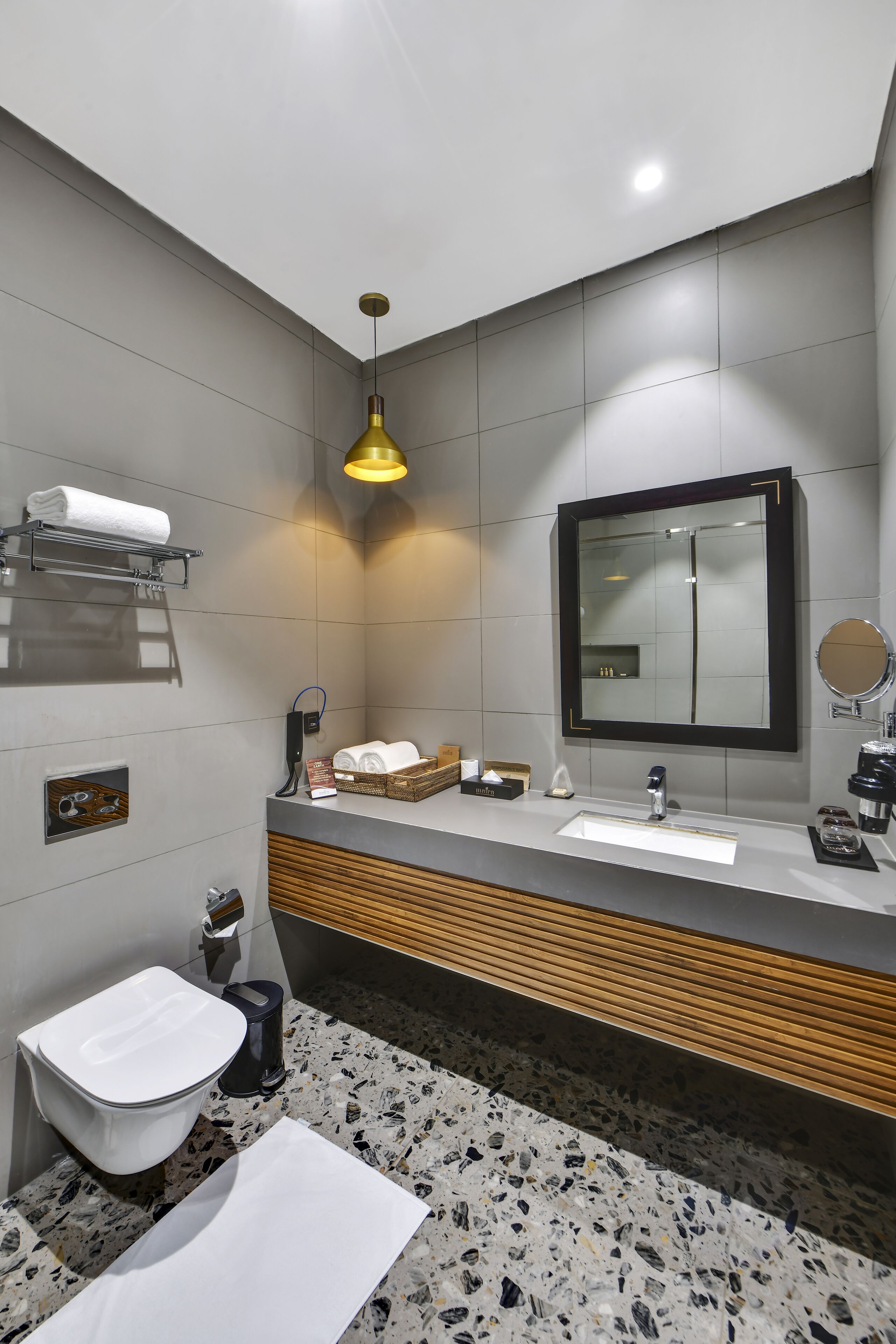 Un baño moderno con un lavamanos blanco, un espejo, un perchero para toallas y un inodoro.