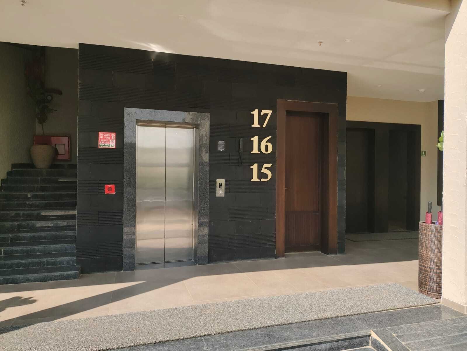 A building entrance with a staircase, an elevator, and a door marked with numbers 17, 16, and 15.