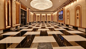A spacious lobby with a checkered floor, a large chandelier, and a large screen displaying a group of people. - Maira Resort and Convention centre (Arang)