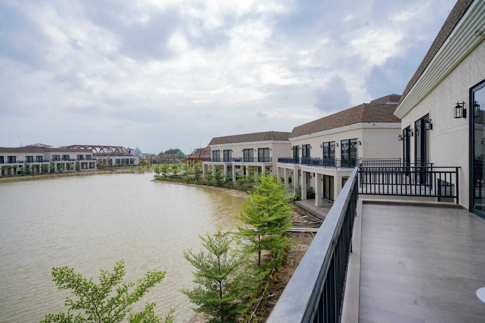 A modern building with a water body in front, featuring balconies and a clear sky.