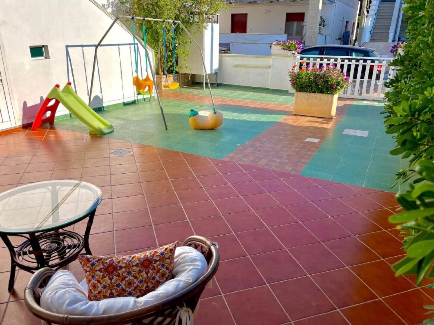 Eine Terrasse mit Schaukel, einem kleinen Tisch und einem gepolsterten Stuhl.
