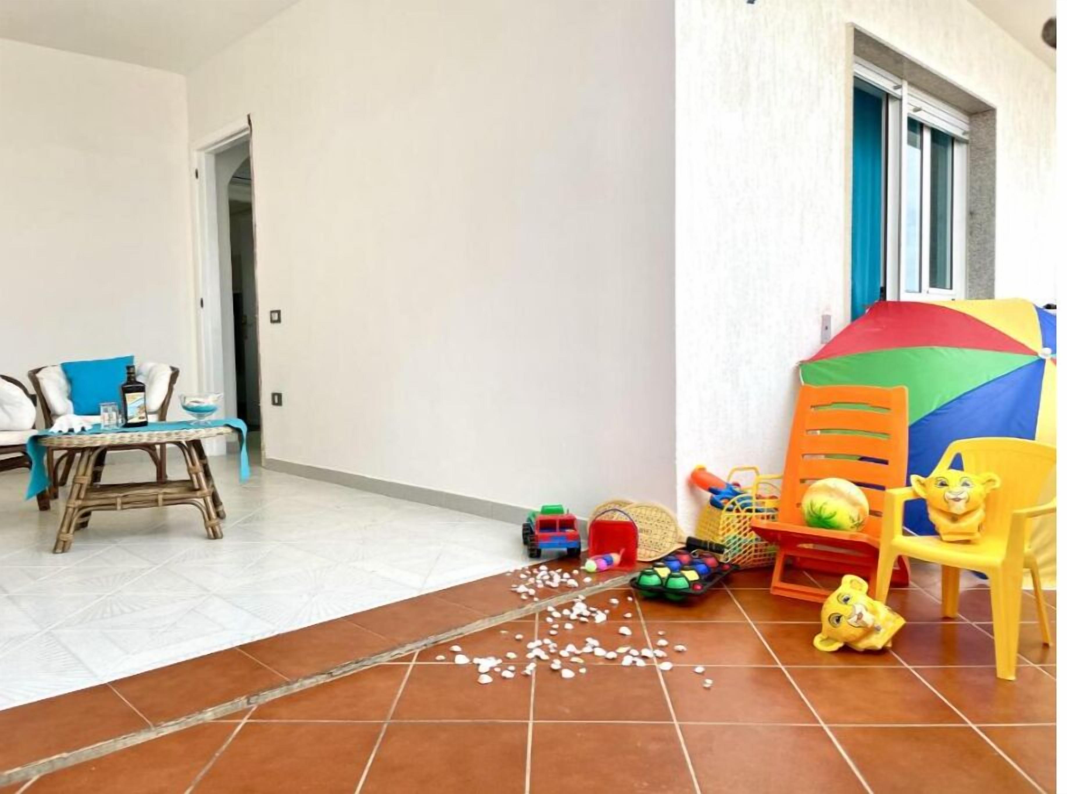 Una sala de estar con un sofá, una mesita, una carpa de juegos colorida y juguetes esparcidos en el suelo.