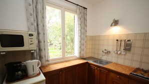 Cocina compacta con microondas, cafetera y lavabo.