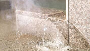 A close-up of a water feature with a clear, flowing stream over a textured stone surface.