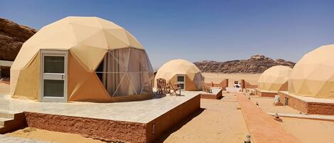A desert resort with geodesic dome accommodations, outdoor seating, and a clear view of the surrounding rocky landscape.