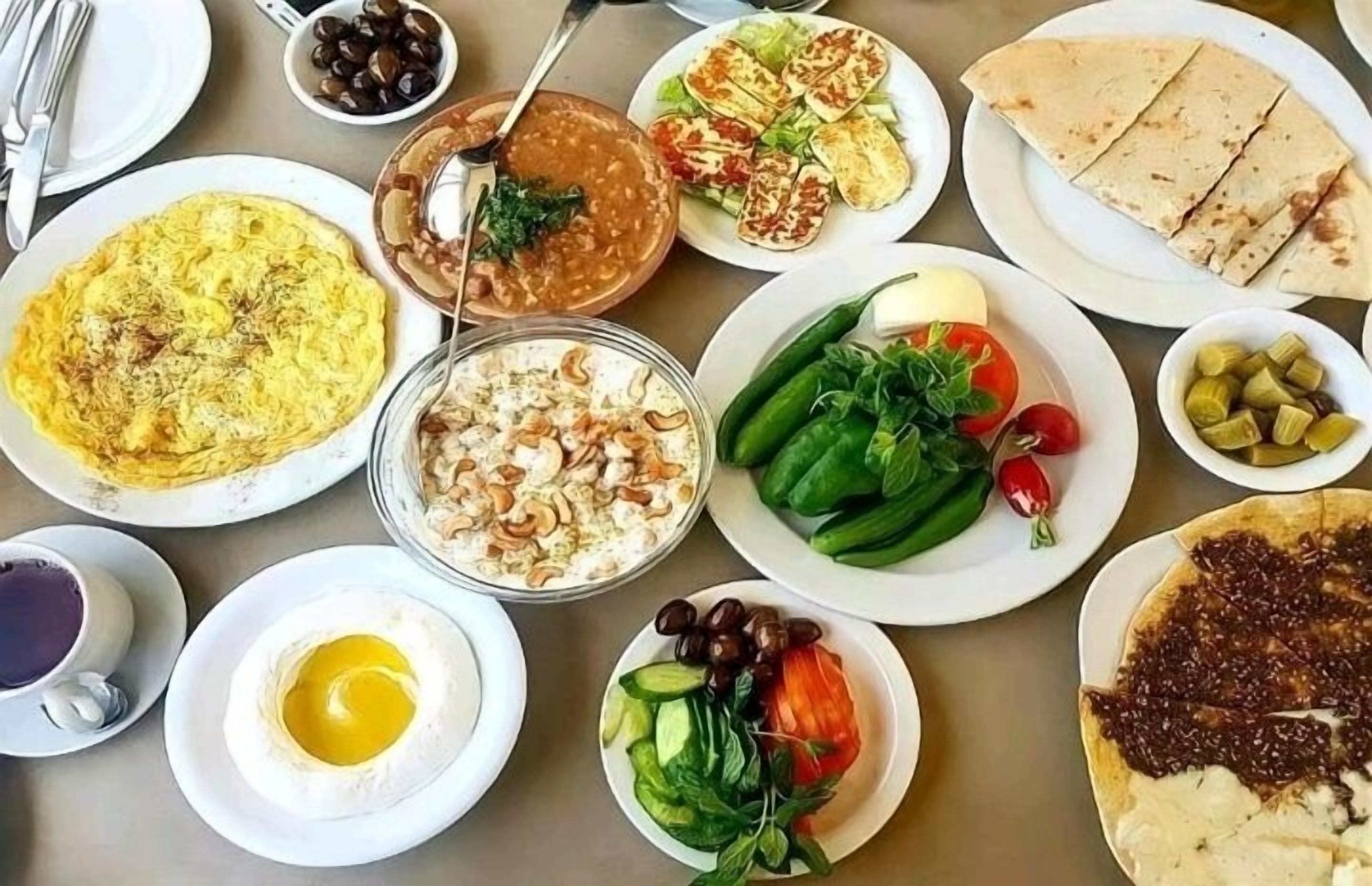 A table with various dishes including a salad, a bowl of soup, and a plate of flatbreads.
