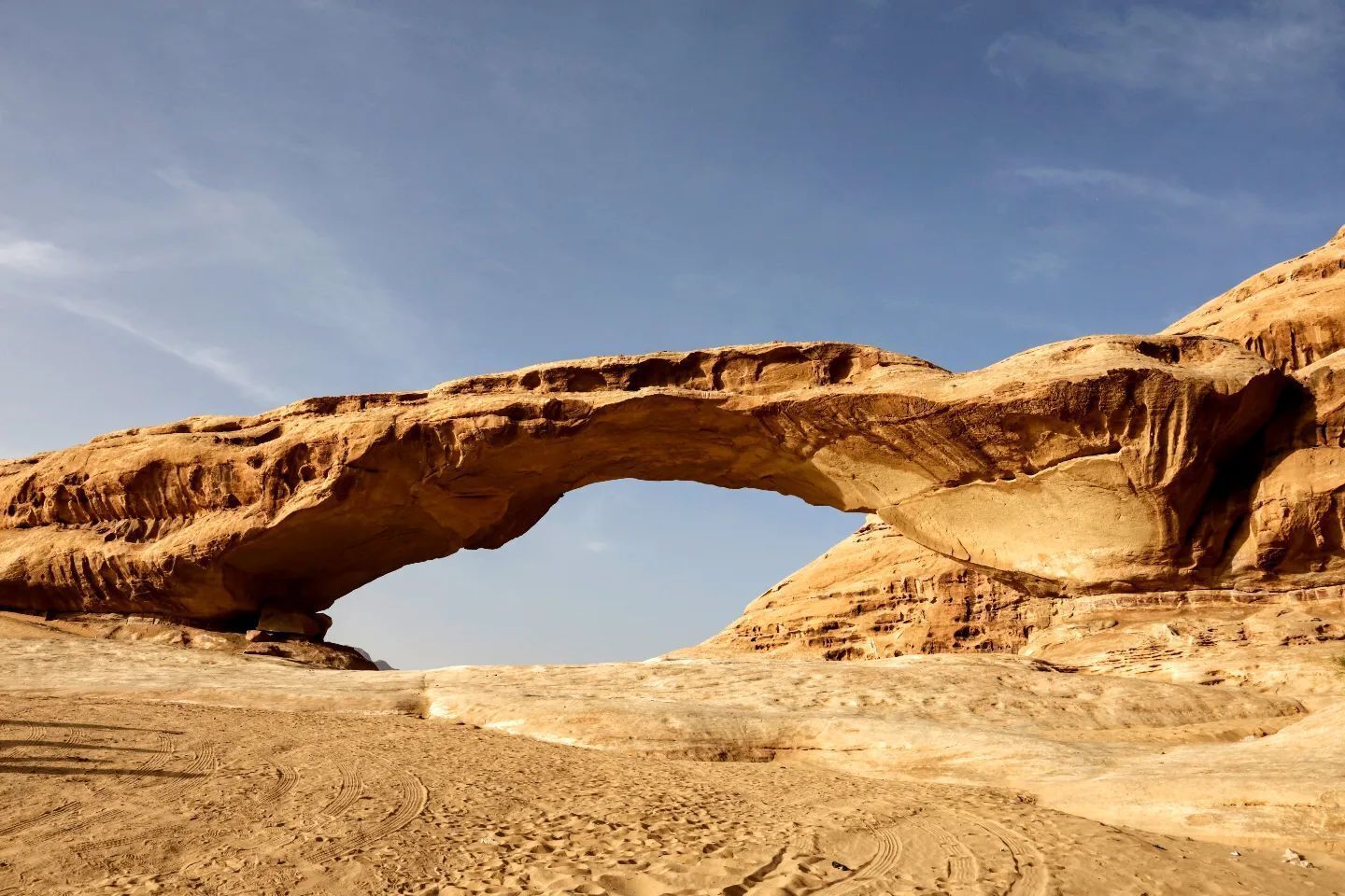 A natural rock arch formation in a desert landscape.
