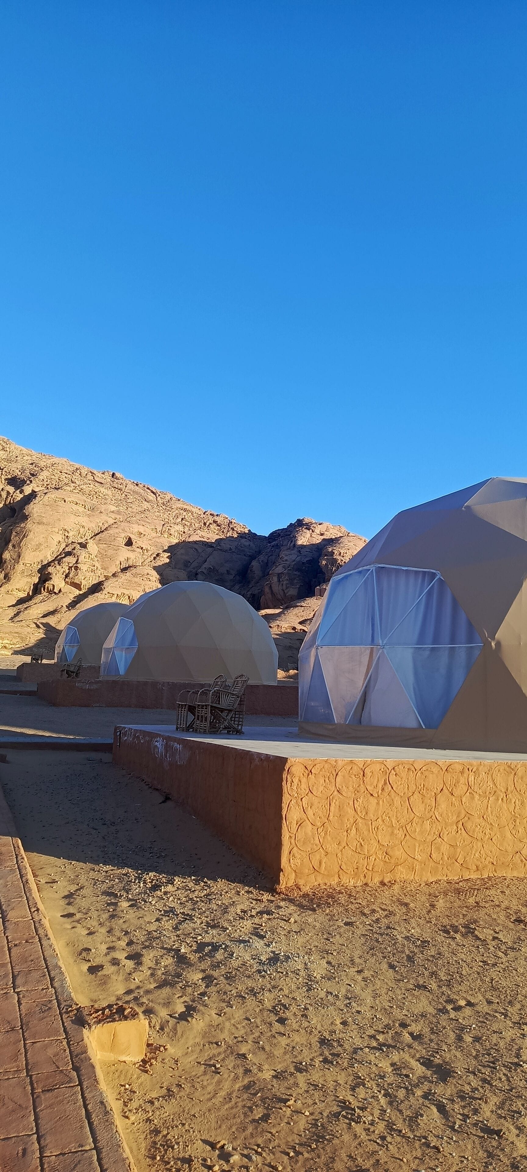 A desert landscape with several dome-shaped tents, some with seating arrangements.