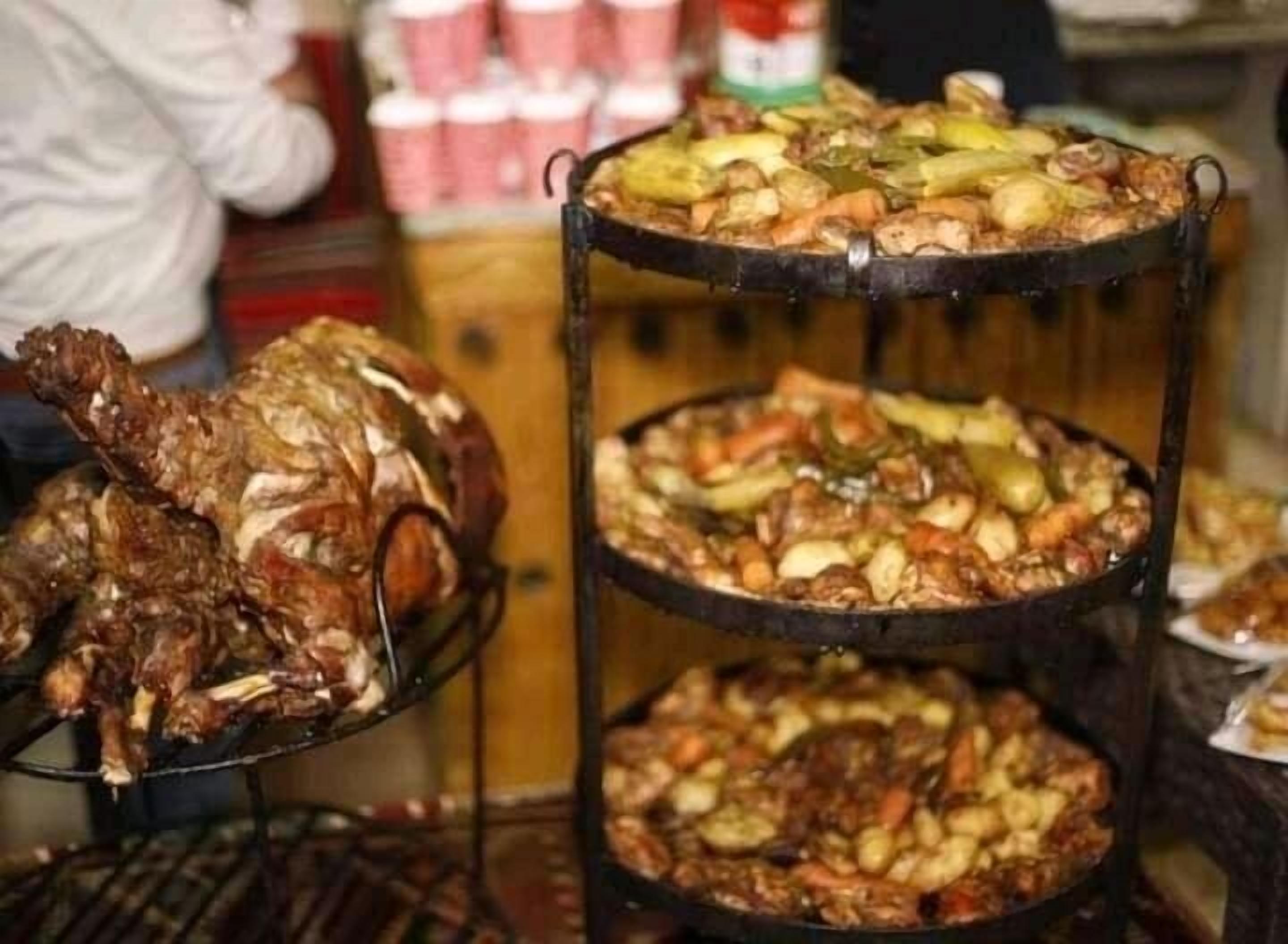 A multi-tiered serving dish with various meats and vegetables.