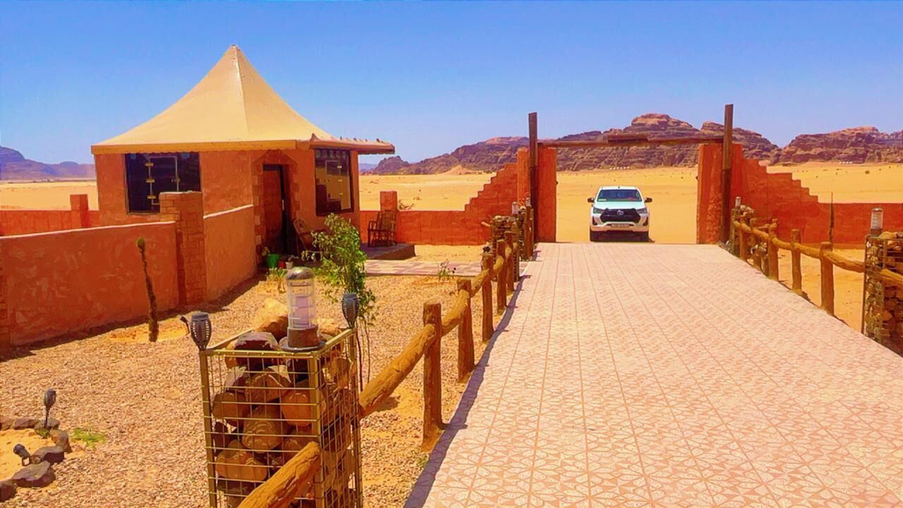 A desert landscape with a building that has a conical roof and a paved entrance.