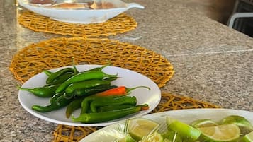 A kitchen counter with woven baskets containing green chili peppers and lime slices.