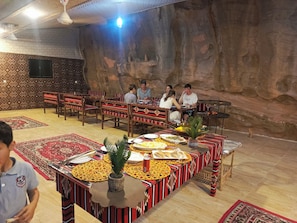 Ein Restaurant mit einer höhlenartigen Innenarchitektur, Holztischen und -stühlen sowie einer Auswahl an Gerichten auf den Tischen.