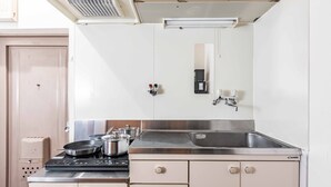 A compact kitchenette with a stove, pots, a sink, and a mirror. - Arita biru daikoku (Osaka)