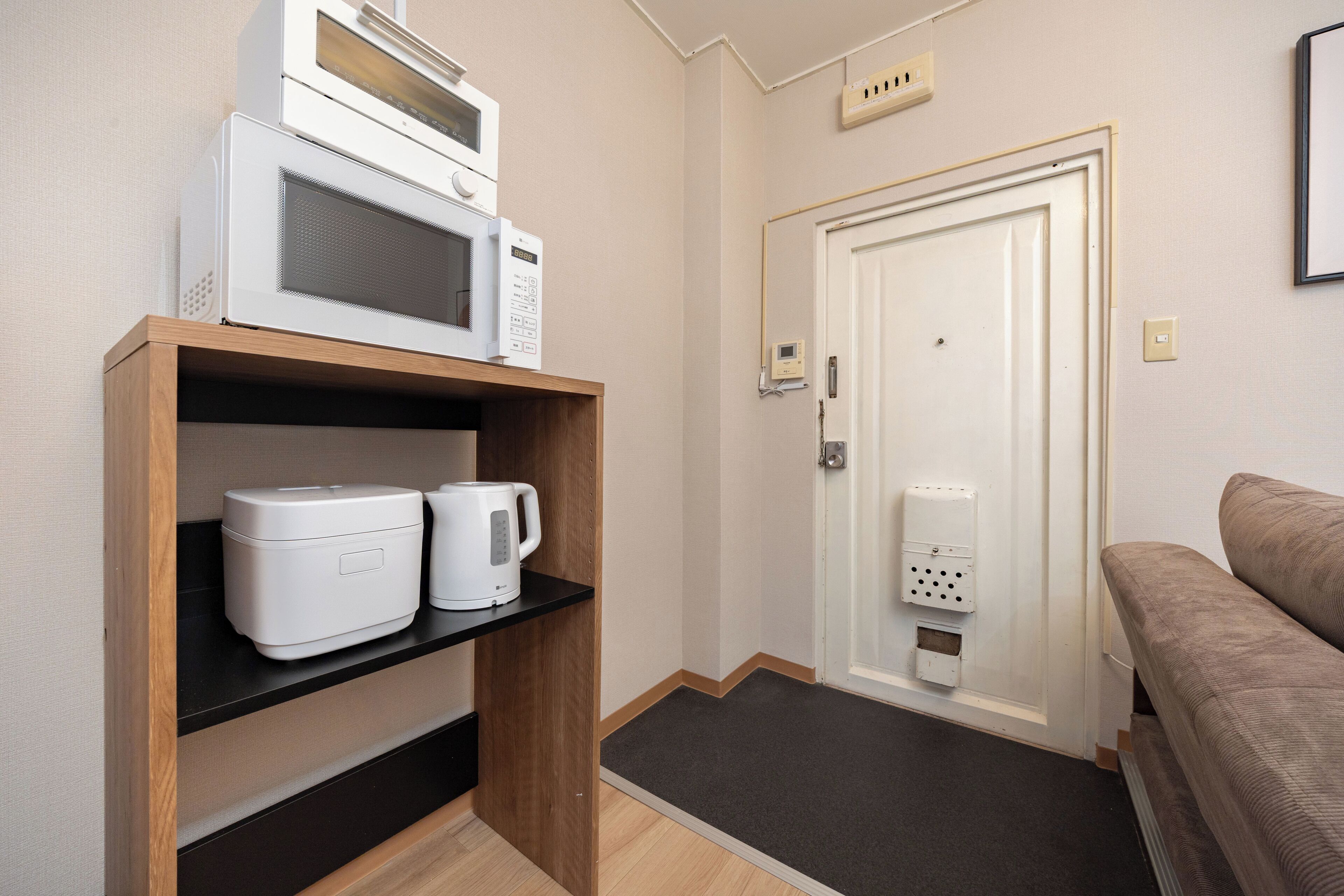 Camera d'albergo con forno a microonde, macchina del caffè e porta dotata di dispositivo di sicurezza.
