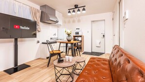 A compact living space with a modern kitchen, a dining area, and a seating area with a leather sofa. - Arita biru daikoku (Osaka)