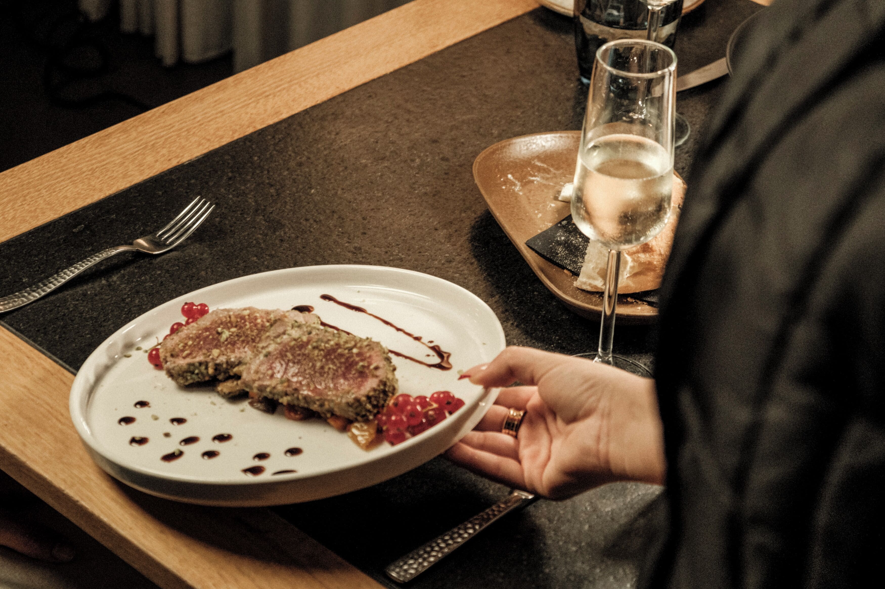 Ein Teller mit Speisen und ein Glas Weißwein auf einem Tisch.