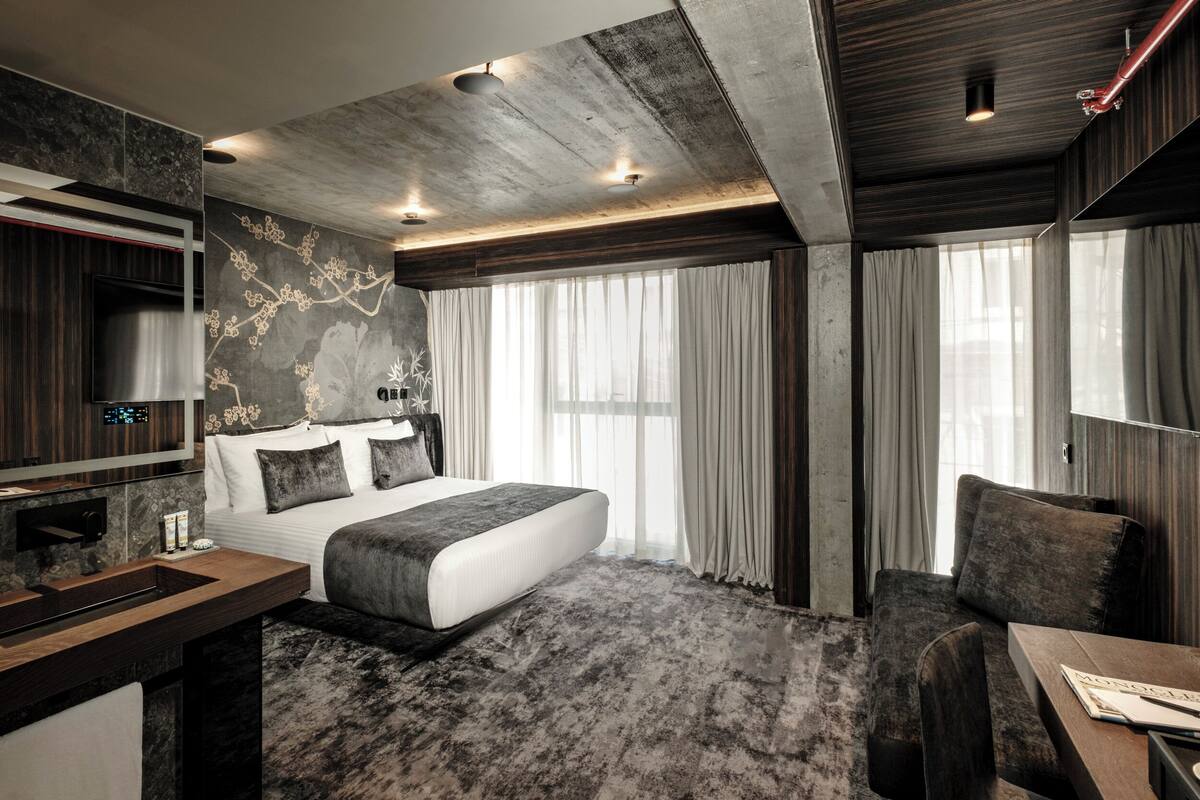 Una habitación de hotel moderna con una cama grande, un escritorio y un baño.