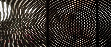 A close-up of a perforated metal structure with a repeating pattern of circular holes.