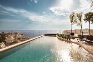 A clear, infinity pool with a view of the sea and a cityscape in the background. - Fitch Hotel (St. Julian's)