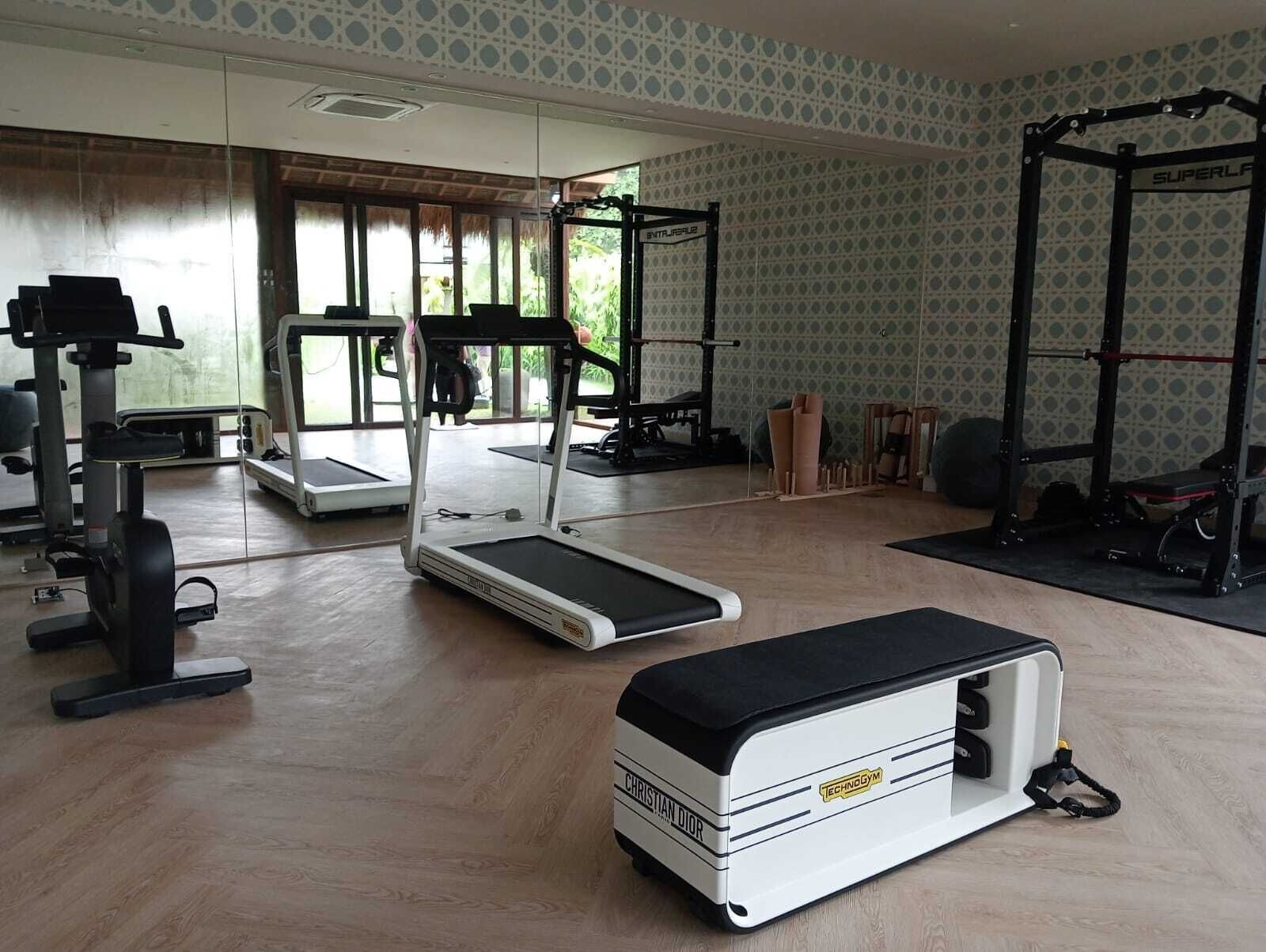 A gym with cardio equipment, weightlifting stations, and a mirror wall.