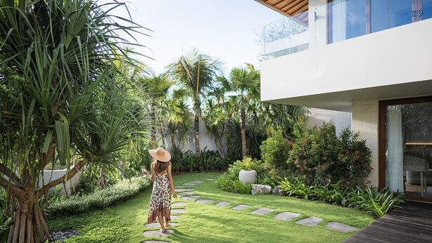 A modern house with a well-maintained garden, stone pathway, and a wooden deck. - Poco Poco Villas by Aayan (Kutuh)