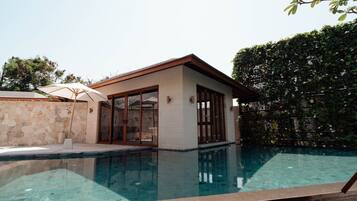 A modern house with a swimming pool, stone wall, and large glass doors.