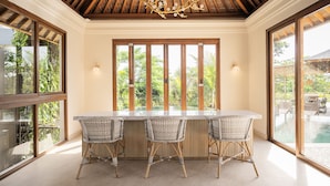 A bar area with a wooden ceiling, large windows, and wicker chairs. - Poco Poco Villas by Aayan (Kutuh)
