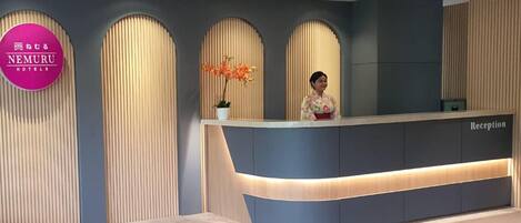 A reception desk with a modern design, featuring a curved counter and a sign that reads "NEMURU HOTELS."