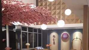 A restaurant with wooden tables and chairs, a large pink decorative tree, and a modern ceiling design.