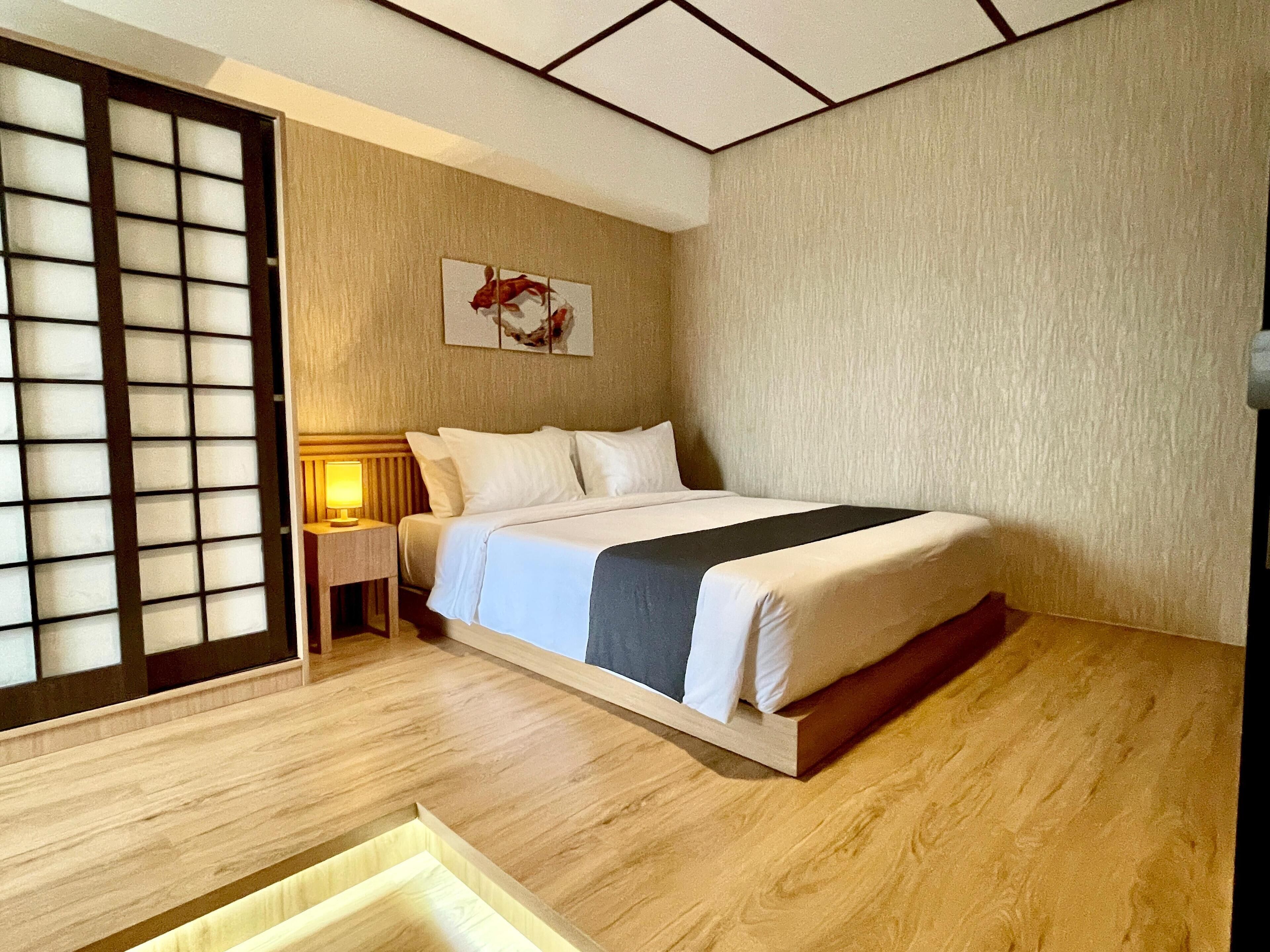 Habitación de hotel con cama, mesita de noche, una obra de arte en la pared y una puerta corrediza.