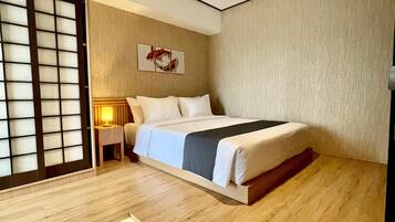 Habitación de hotel con cama, mesita de noche, una obra de arte en la pared y una puerta corrediza.
