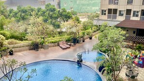 A circular pool with a tiled edge, surrounded by potted plants and outdoor furniture.