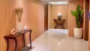 A modern hallway with wooden paneling, a console table with decorative items, and a potted plant.