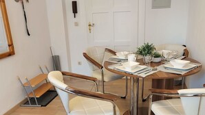 A dining area with a round table, white cushioned chairs, and a small potted plant. - Apartment Amina by Interhome (Braunlage)