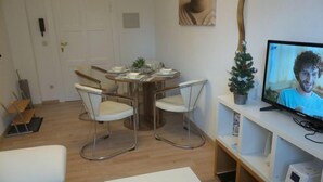 A modern living room with a dining table, two chairs, a sofa, a television, and a small Christmas tree. - Apartment Amina by Interhome (Braunlage)