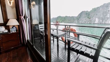 A wooden deck with a table and chairs, a wooden dresser, and a window with curtains.