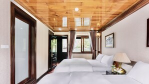 Een hotelkamer met een houten plafond, twee bedden, een nachtkastje met een lamp en een schilderij aan de muur.