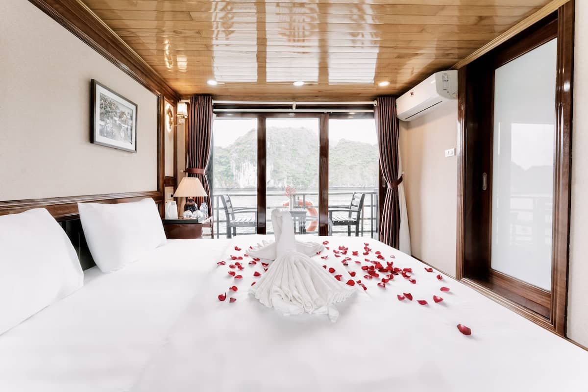 Una habitación de hotel con una cama, un cuadro en la pared y vistas a las montañas desde la ventana.