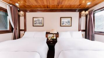 A double bed with white linens, a nightstand with a lamp, and two framed pictures on the wall.