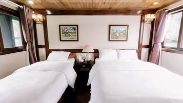 A hotel room with two beds, wooden ceiling, wall-mounted lamps, and framed artwork.
