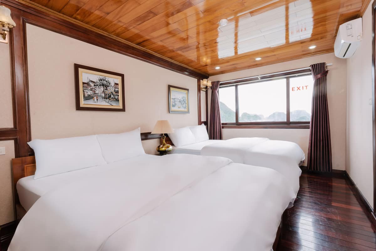 Habitación de hotel con dos camas, techo de madera, cuadros enmarcados en la pared y un letrero de salida.