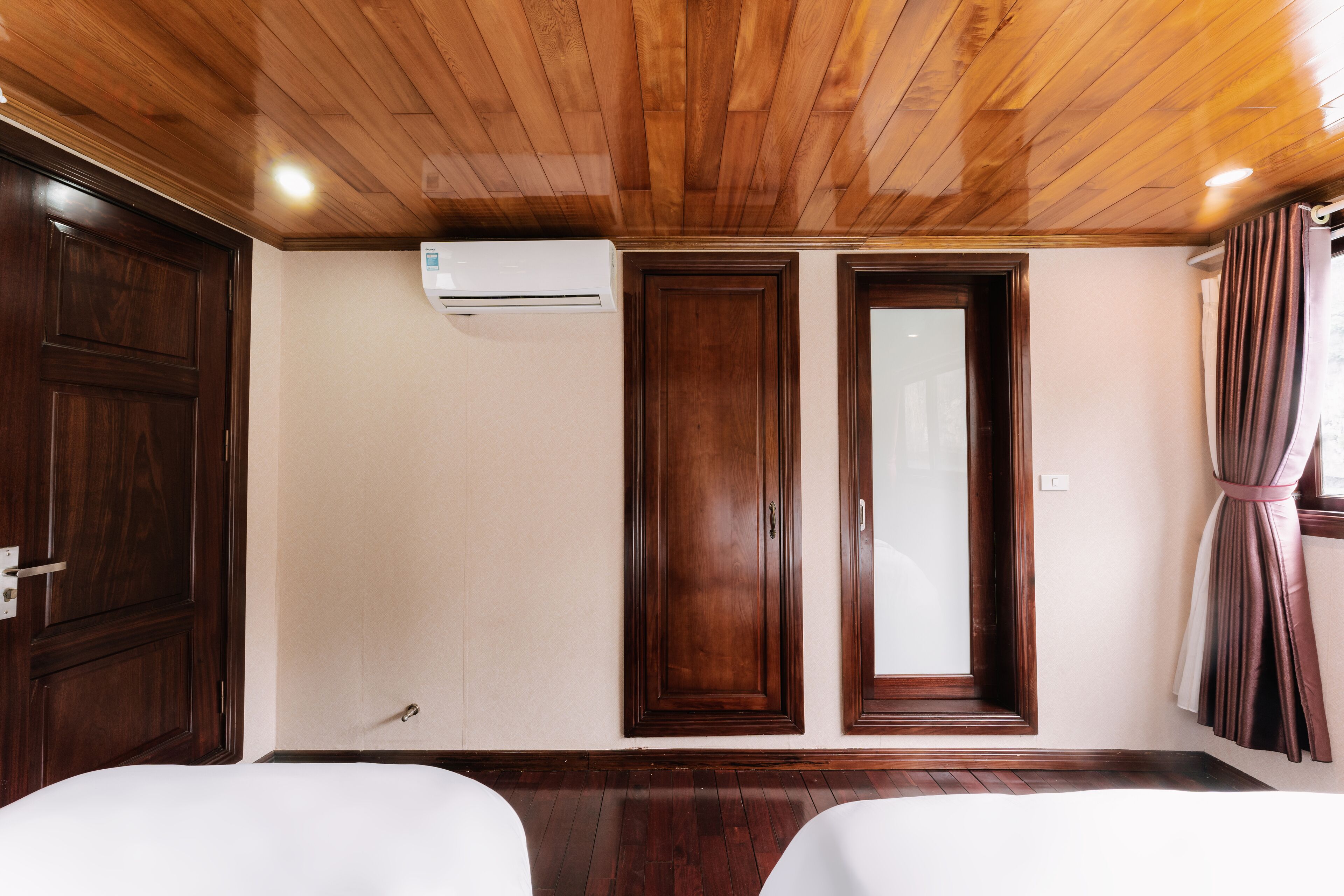 Une chambre d’hôtel avec un plafond en bois, deux portes, un appareil de climatisation et un lit.