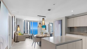 Una cocina moderna con una isla central, iluminación colgante y vista al mar.