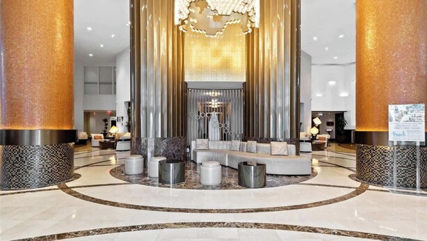 A spacious lobby with a central seating area, a chandelier, and a reception desk. - New! Modern Beach Resort - Ocean View & Access (Sunny Isles Beach)