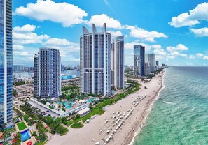 A coastal cityscape with high-rise buildings, a beach, and a marina.