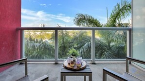 Un balcon avec une table, des chaises et une vue sur les palmiers et les immeubles.
